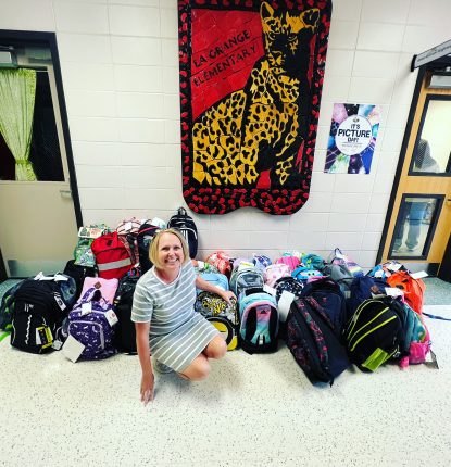 Member of Hunting Creek sits in front of some school supplies that were donated for the Back to School drive.